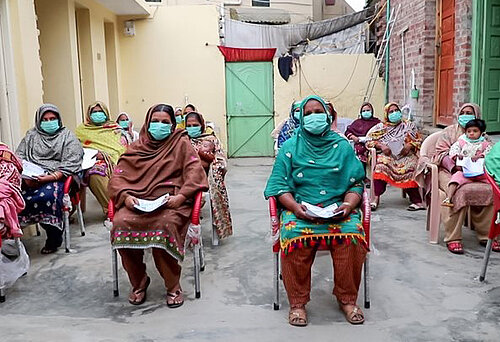 Frauen mit Mundschutz nehmen in einer pakistanischen Community an einem Workshop zur Aufklärung gegen das Coronavirus teil
