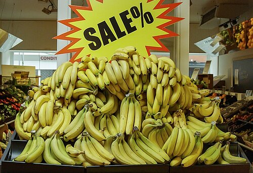 Bananen in einem Supermarkt, die mit großem "Sale"-Schild angeboten werden