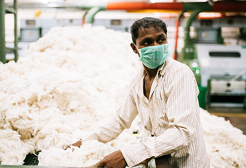 Ein indischer Textilarbeiter sortiert Baumwolle.