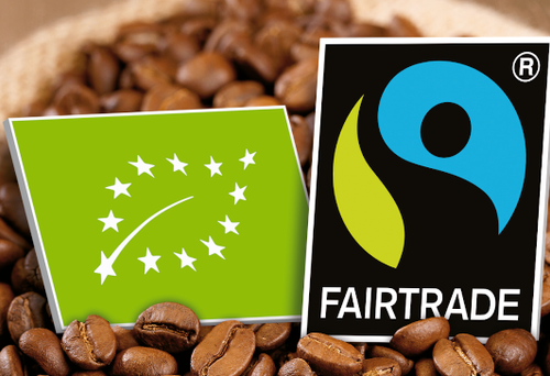 Ein Bio-Siegel liegt neben einem Fairtrade-Siegel in einem Sack Kaffeebohnen. 