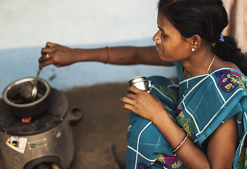 Eine indische Frau kocht mit einem modernen Kochofen.